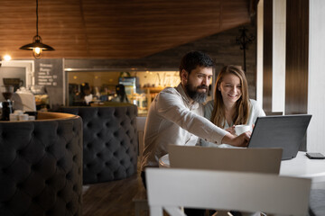 Two smiling creative workers discussing a project during a meeting in a cafe