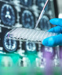 © Connect Images - Close-up of gloved hand holding pipette and test tubs in front of brain scans