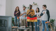 © silverkblack - Multi-ethnic group of friends sport fans listening and singing German national anthem before watching sports championship on TV together at home indoors