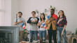 © silverkblack - Multi ethnic group of friends sport fans listening and singing French national anthem before watching sports championship on TV together at home indoors
