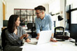 © JustLife - Colleagues in office. Businesswoman and businessman discussing work in office..