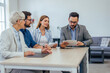 © bnenin - Group of businesspeople working together in the meeting room, looking concentrated.