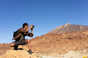 Young man taking pictures on a road trip. Man making memories on the mountain..