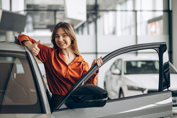 Woman choosing a car in a car showroom