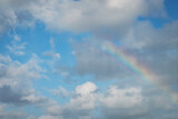 Fototapeta Tęcza - Tęcza na tle błękitnego nieba z białymi kłębiastymi chmurami.