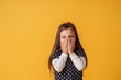 © skif - portrait of a cute little girl covering her mouth with both hands stands on yellow background. The child doesn't want to talk. Keeps a secret, learned a secret
