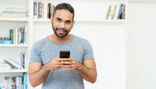Handsome Hispanic Hipster Man With Beard Sending Message At Mobile Phone