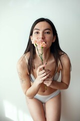 Portrait of young beautiful woman holding flower over grey background.