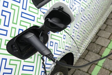 Sticker - Close up of plugin recharging an electric car, focus on plugin, green mobility