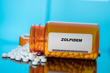 Zolpidem White Medical Pills And Tablets Spilling Out Of A Drug Bottle. Macro Top Down View With Copy Space.
