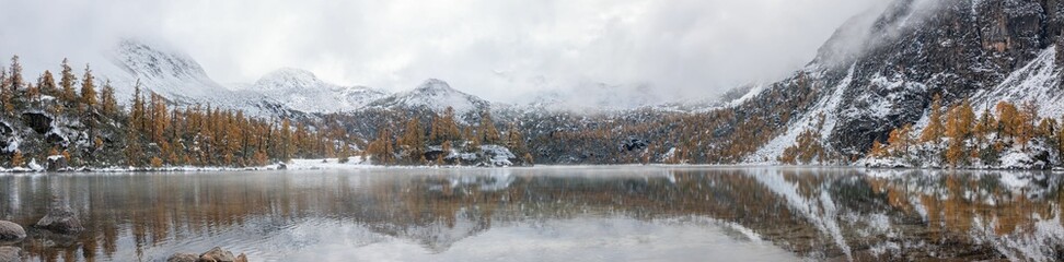 Panoramic shot of a beautiful winter scenery with an alpine lake surrounded by trees