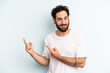 © kues1 - young adult bearded man smiling happily and pointing to side and upwards with both hands showing object in copy space