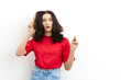 a sad, upset woman is trying to comb her long, dark, tangled hair with a wooden massage comb, standing in a red T-shirt on a white background and making a sad, funny face