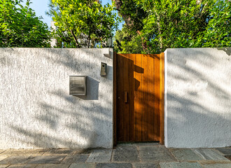 Poster - Contemporary house exterior entrance with a natural brown wood door, Athens, Greece.