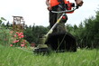 A gardener mows the grass in the garden with a brushcutter.
Ogrodnik kosi trawę w ogrodzie za pomocą wykaszarki.