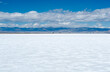 Glittering white Salt Flats in Utah, United States with cars and trucks on a highway in the distance.