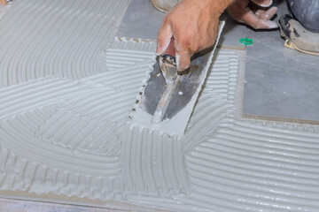 Renovation works with the adhesive on the bathroom floor is sprayed onto wet mortar before tiles are applied