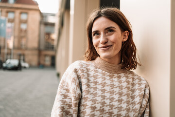 Wall Mural - Young woman leaning against a wall and looking forward laughing