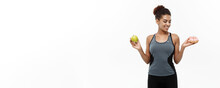 Healthy And Diet Concept - Beautiful Sporty African American Make A Decision Between Donut And Green Apple. Isolated On White Background.
