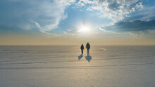 The Two Travelers With Backpacks Walking Trough The Snow Field