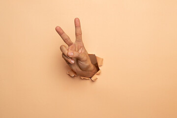 Wall Mural - man hand showing two fingers,victory sign gesture on a brown background,