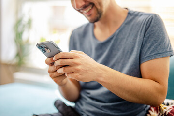 The guy sends messages from a modern smartphone in a bright modern home interior - the concept of chatting via social media