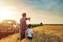 Father And Son Outdoor On Wheat Field. Farmers Life Concept. Father Showing Their Land To His Son