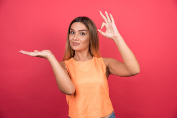 Wall Mural - Pretty young woman making ok sign on red background