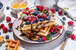 Sweet waffles with berry. Homemade summer breakfast belgian waffles with raspberries, blueberries, strawberry honey and chocolate dip sauce, copy space