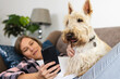 © Wavebreak Media - Caucasian mid adult lesbian couple using cellphone while relaxing with scottish terrier on sofa