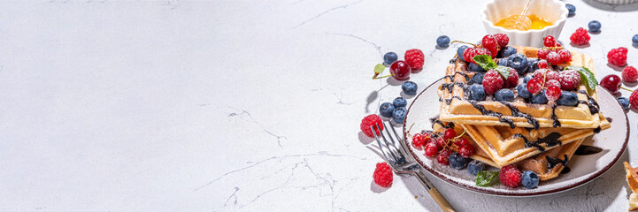 Sweet waffles with berry. Homemade summer breakfast belgian waffles with raspberries, blueberries, strawberry honey and chocolate dip sauce, copy space