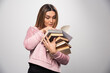 © rastockinc - Girl in pink swaetshirt holding a stock of books and trying to read the top one with a magnifier