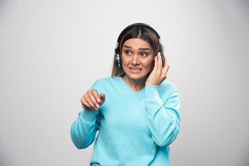 Wall Mural - Blonde girl in blue sweatshirt posing with headphones