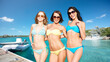 © Syda Productions - travel, tourism and summer vacation concept - beautiful happy women or female friends in bikinis and sunglasses posing over wooden pier and boat on tropical beach background in french polynesia
