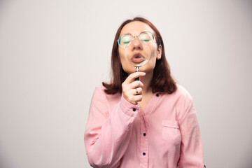 Wall Mural - Portrait of woman holding a magnifying glass on a white background