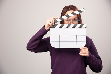 Wall Mural - Young woman posing with a cinema tape on a white background