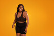Happy plus size woman posing in sporty black fashionable clothes, smiling to the camera. Sports and weight loss concept.