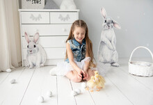 Little Smiling Cute Girl With Long Blond Hair In Denim Vest Playing With Three Yellow Ducks  In White Studio