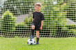 Cute boy playing football enjoying sport game outside