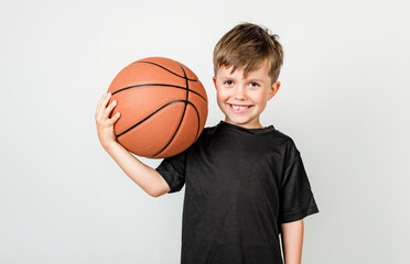 Portrait of smiling little boy with basketball ball over grey background