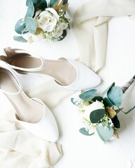 Top view of classy shoes and flower decorations for a wedding on a white background