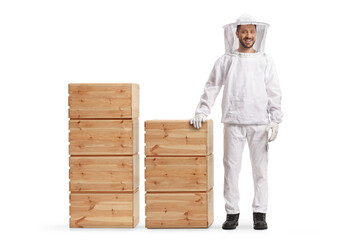 Wall Mural - Bee keeper in a uniform standing next to wooden crate piles