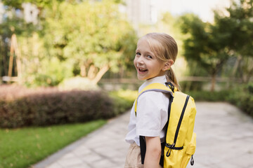 Schoolgirl back to school after summer vacations. Pupil in uniform smiling early morning outdoor. 