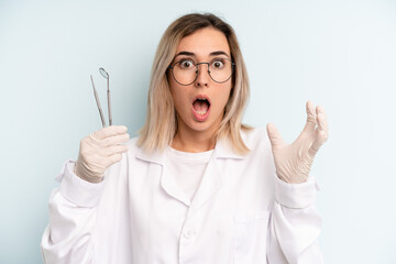 blonde woman feeling extremely shocked and surprised. dentist concept