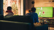 © Gorodenkoff - Couple of Soccer Fans Relax on a Couch, Watch a Sports Match at Home in Stylish Loft Apartment. Relaxed young Man and Woman Cheer for Their Favorite Football Club and Enjoying the Weekend.