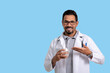 © Edson Souza - nutritionist points to a glass of water that he is holding, male doctor, holding a glass of water, smiling and looking at the camera, blue background