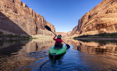 Adventurous Woman on a Kayak paddling in Colorado River. Glen Canyon, Arizona, United States of America. American Mountain Nature Landscape Background. Adventure Travel