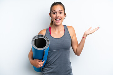 Young sport woman going to yoga classes while holding a mat isolated on white background with shocked facial expression