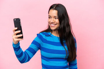 Young Colombian woman isolated on pink background making a selfie