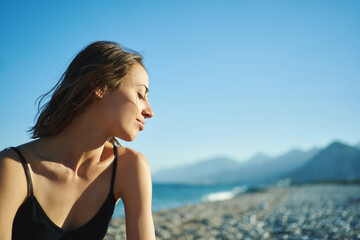 Wall Mural - Outdoor portrait beautiful summer girl enjoying weekend at beach with mountains by the sea